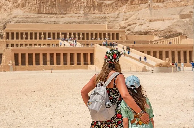 Zwei Besucher von hinten, die bei hellem Sonnenlicht zum Hatschepsut-Tempel hinaufschauen