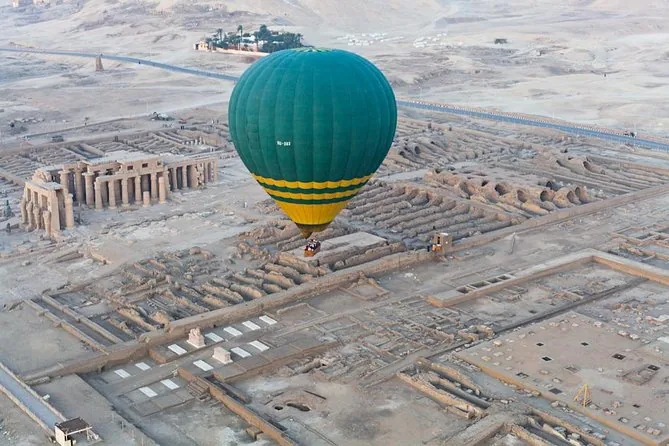 Una mongolfiera verde e gialla che fluttua sopra le rovine del Ramesseum viste dall'alto