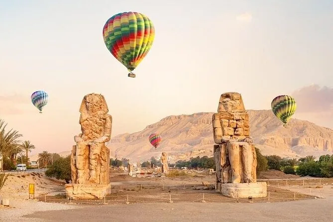 I due Colossi di Memnone in un campo con mongolfiere nel cielo dietro